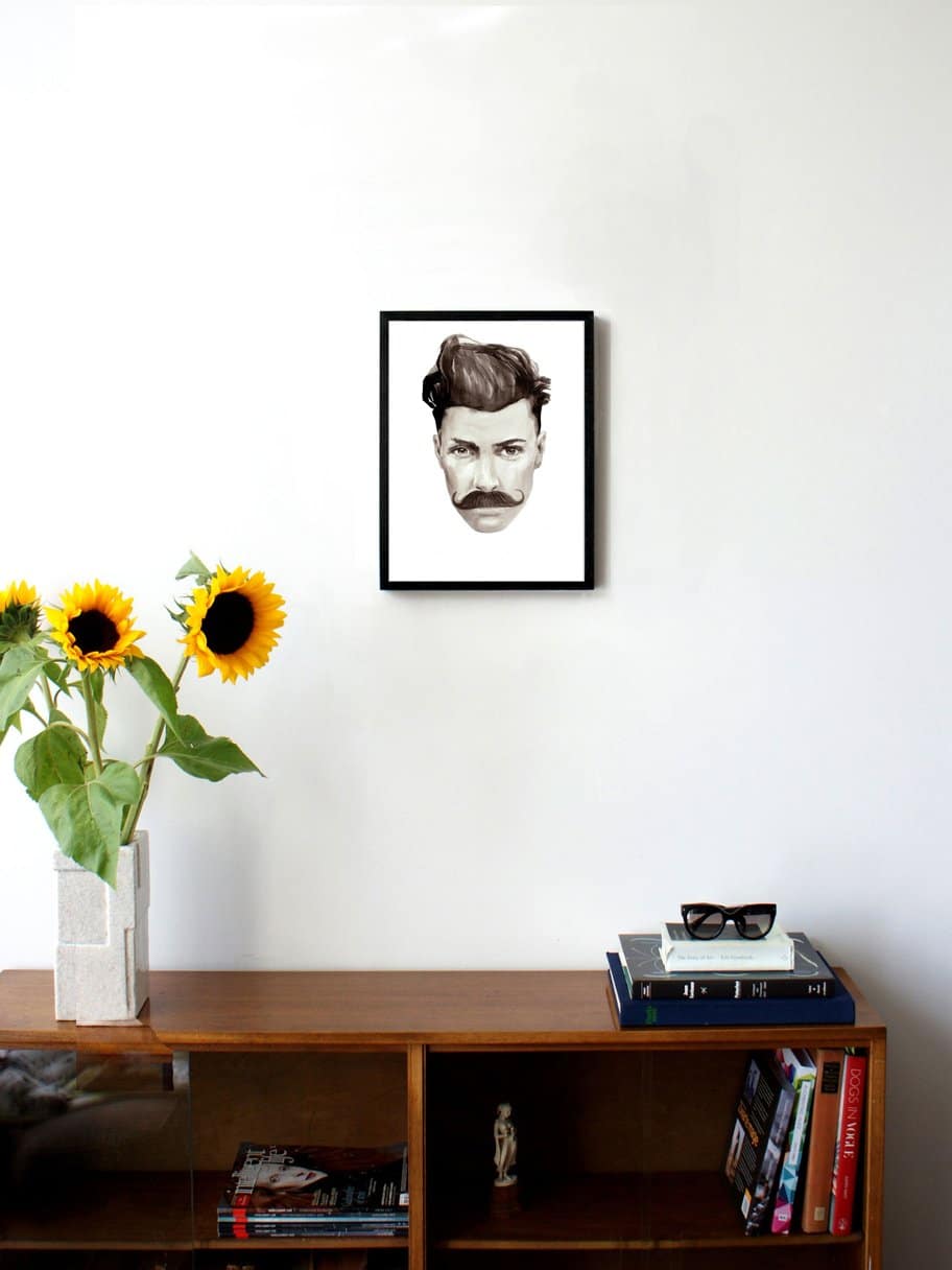 black and white illustrated portrait of a man with a moustache hanging on a wall in the living room