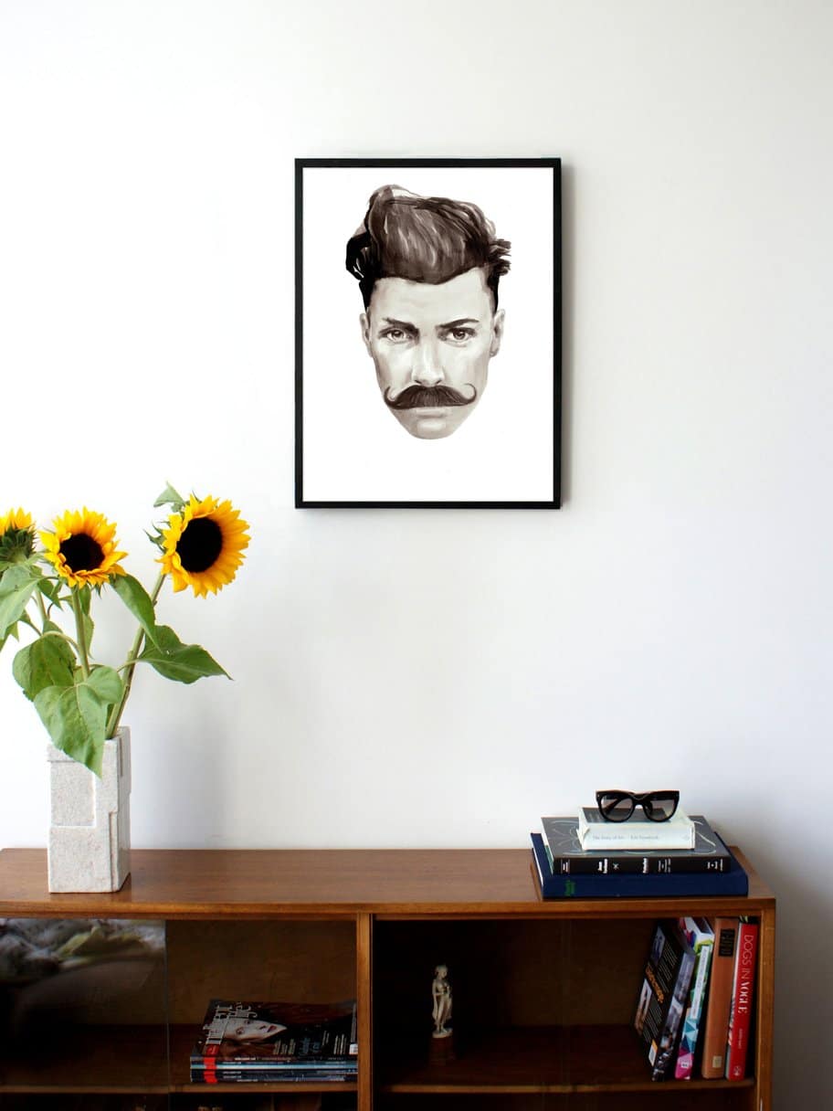 black and white illustrated portrait of a man with a moustache hanging on a wall in the living room