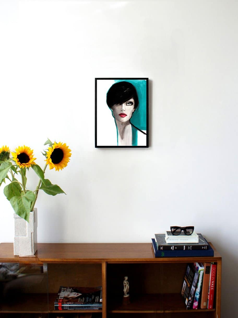 illustration of a woman with short dark hair and blue details hanging on a wall in the living room