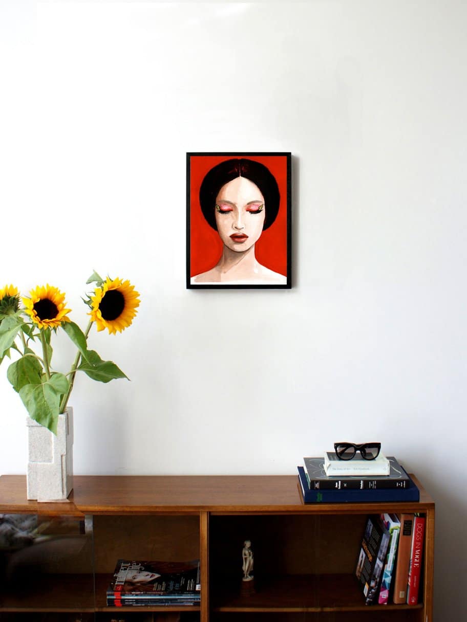 illustration of a woman with dark hair and eyes closed with a red background hanging on a wall in the living room