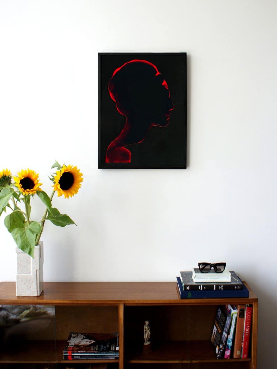 illustration of a silhouette of a womans head from the side with black background and red glow hanging on a wall in the living room