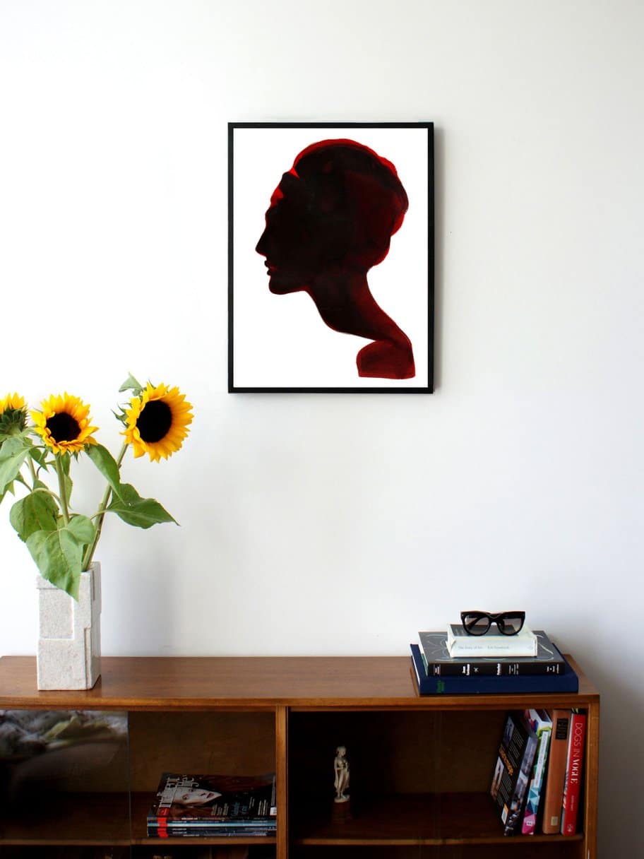 an illustration of a silhouette of the side of a womans face hanging on a wall in the living room