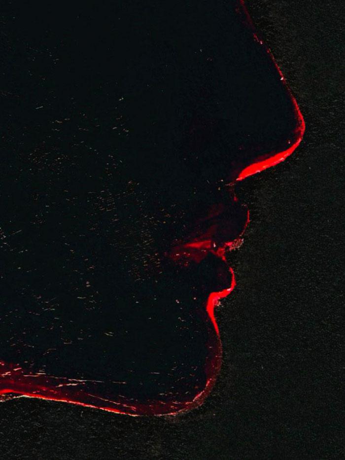 illustration of a silhouette of a womans head from the side with black background and red glow detail mouth